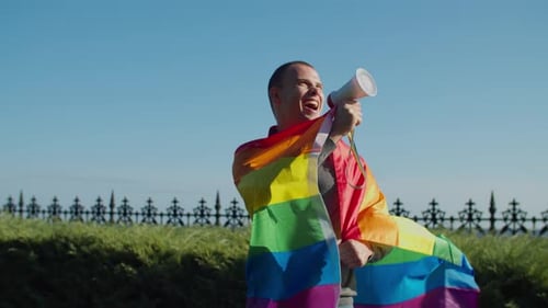 Smiling Man Speaking into Megaphone with Rainbow Flag