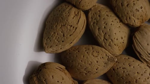 Cinematic, rotating shot of almonds on a white surface
