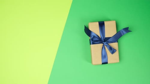 female hand puts on green surface wrapped gifts with blue tied ribbons