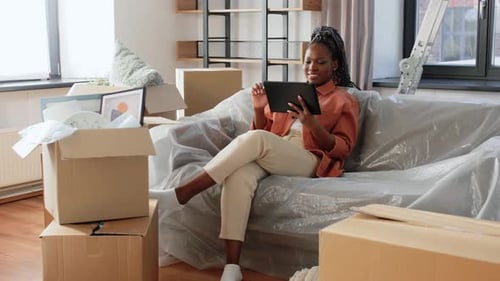 Woman Using Tablet Surrounded by Moving Boxes