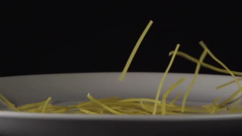 Uncooked Pasta Falling onto White Plate