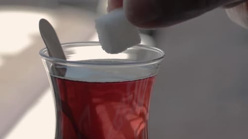man puts sugar cubes in a glass of tea