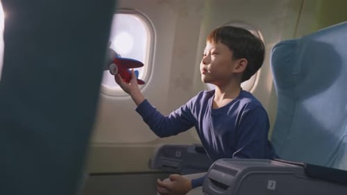 Boy Plays with Toy Plane on Airplane Flight