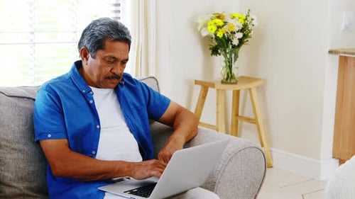 Senior Man Using Laptop on Couch at Home