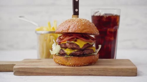 Hamburguesa fresca y sabrosa servida con refresco y papas fritas en una mesa blanca