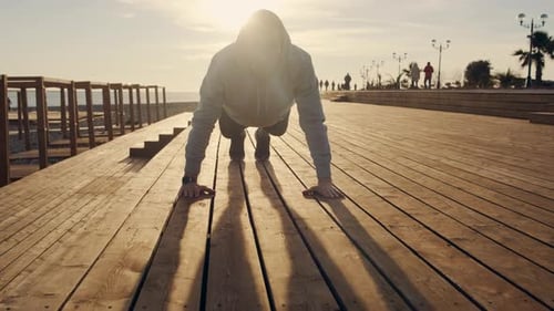 Male Athlete Is Doing Push Ups on City Embankment Near Sea in Sunny Evening
