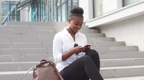 Young Woman Using Phone on Steps Outside