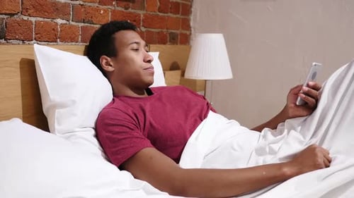 Young Adult Using Smartphone in Bed