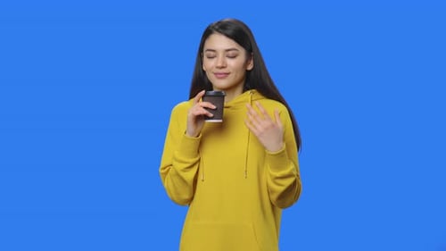 Smiling Woman Enjoying Coffee Against Blue Background