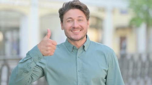 Man Smiling and Giving Thumbs Up in City