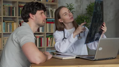 Doctor Reviews X-Ray with Patient in Office