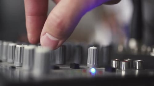 Hand Adjusting Audio Mixer Faders in Studio