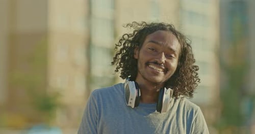 Smiling Man with Headphones in Urban Setting