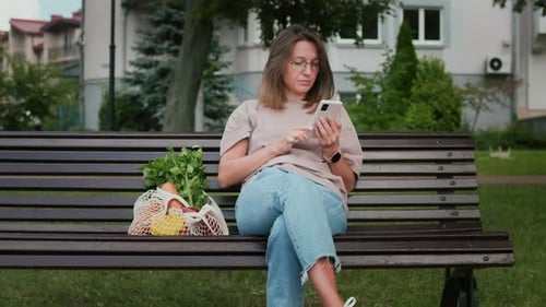 Mujer con smartphone y bolsa de compras con cuerdas