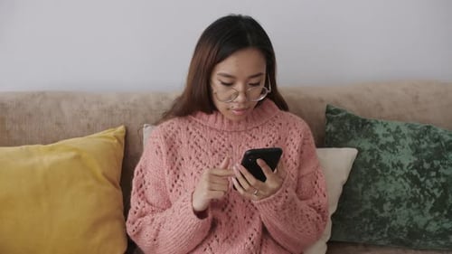 Woman Using Cell Phone Relaxing on Couch Indoors