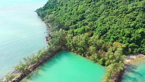Beautiful turquoise lagoon for children to swim, surrounded by rocks and tropical plants near shore