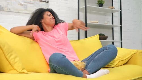 Woman Dancing on Couch at Home with Chips