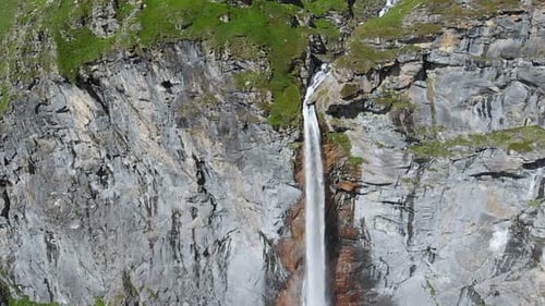 Aerial slow motion: drone flying over scenic waterfall and mountain stream on the italian Alps