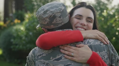 Woman Smiling Embracing Soldier in Camouflage Uniform