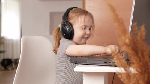 Child Listens to Music in Headphones Dances Rejoices and Smiles