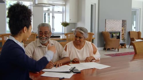 Mixed race female real estate agent discussing over property with senior couple at home 4k