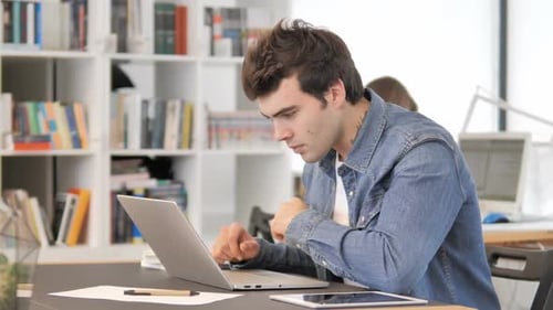 Frustrated Man Working on Laptop in Office