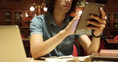 Young Adult Using Tablet in Library Setting