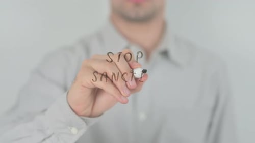 Writing Stop Sanctions with a Marker on Glass