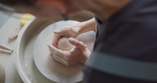 Une potière façonne un morceau d'argile sur la roue à poterie.