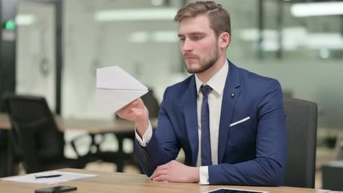 Young Adult Holds Paper Airplane in Office