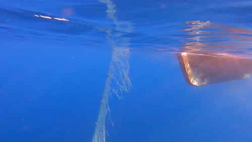 Fishing Net Hanging From Boat Under Sea in Underwater