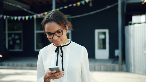 Joyful African American Girl Using Smartphone Outdoors in Street Touching Screen