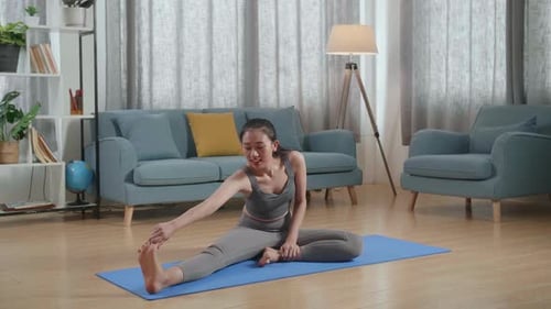 Woman Stretches on Yoga Mat in Living Room