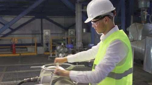 At the factory, the engineer opens the valve.