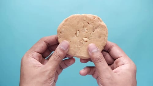Hands Breaking Cookie with Nuts in Close Up
