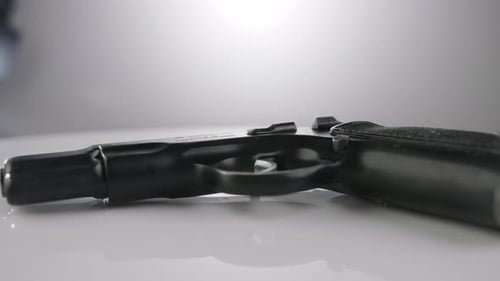 Waffenkontrolle. Studioaufnahme einer 9-mm-Pistole, die sich auf einer reflektierenden Oberfläche dreht