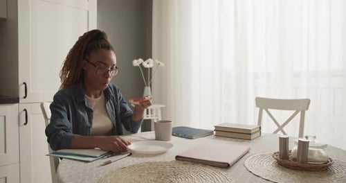 Woman Enjoys Breakfast While Studying at Home
