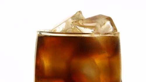 Pouring a Refreshing Brown Drink over Ice