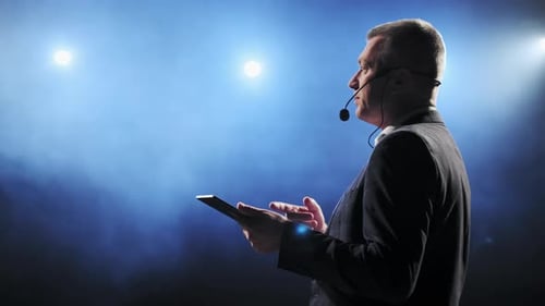 Man Speaking at Corporate Presentation Holding a Tablet