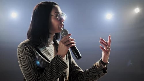 Woman Giving Presentation With Microphone On Stage