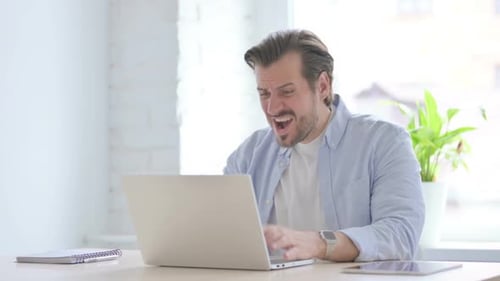 Man Working on Laptop Frustrated at Desk