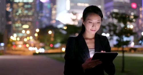 Woman Using Tablet in City at Night