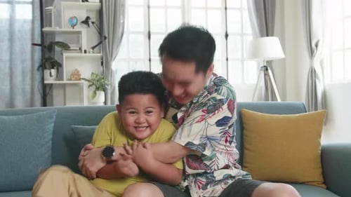 Loving Father and Son Embracing on Couch at Home