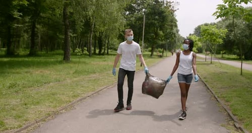 Voluntarios adolescentes llevan una bolsa de basura en un parque