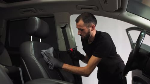 Dry Cleaning the Car Interior a Man Applies Foam To Treat the Leather Seat of a