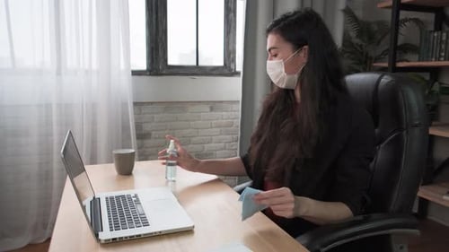 Woman Cleans Laptop with Wipe in Home Office