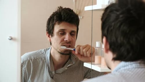 Man Brushing Teeth in Front of Bathroom Mirror