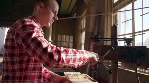 Man Using Drill Press in Bright Workshop