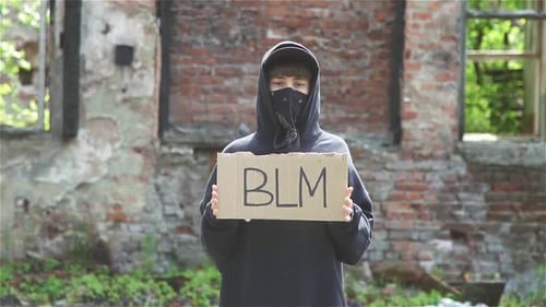Teen Holding BLM Sign in Urban Ruins