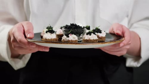 Chef Holds Caviar Canapés on Plate